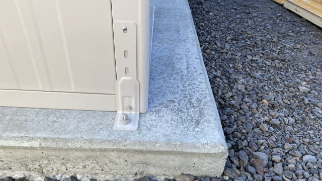 コンクリート基礎にアンカーボルトを打ち込んで物置を固定した画像