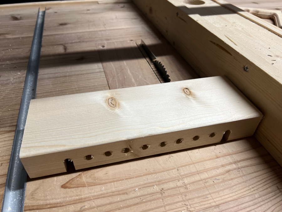 穴あけした木材をテーブルソーでカットして溝を作る様子