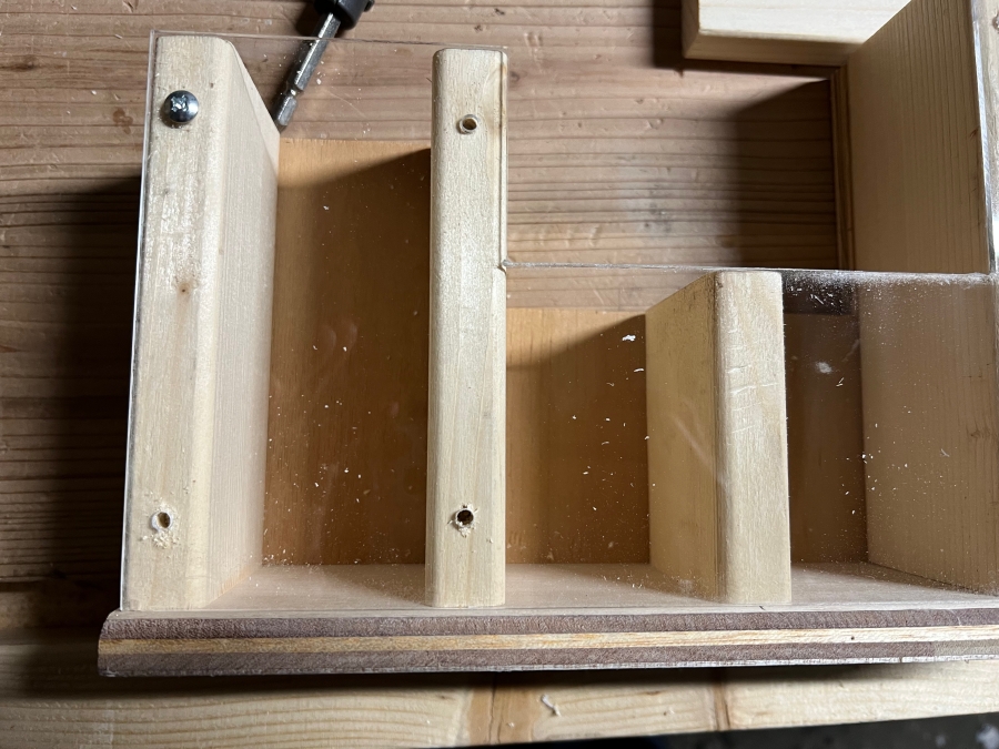 鍋ネジを使って木材にアクリル板を固定する様子