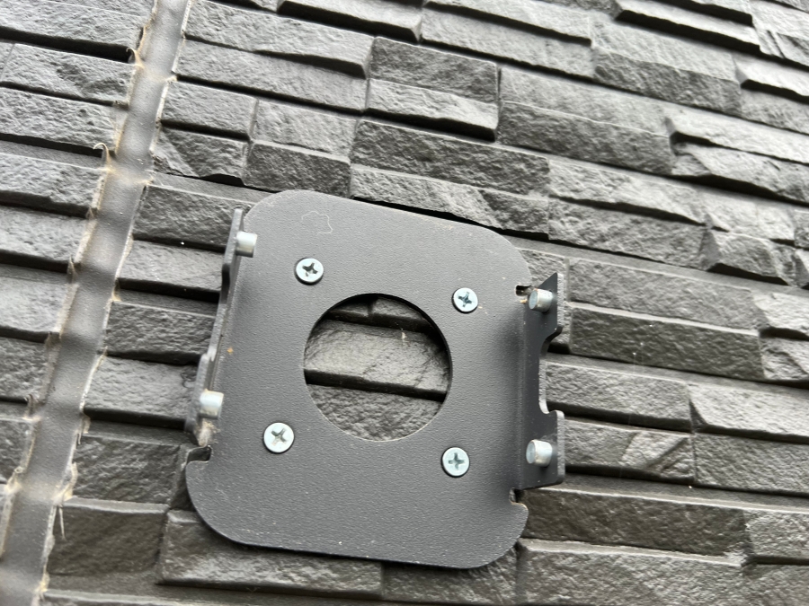 サイディングにソーラー防犯カメラを固定するためのベースをネジで取り付けた様子