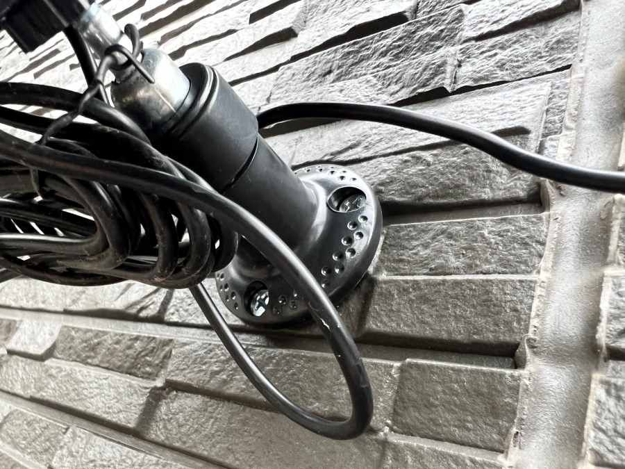 サイディングに防犯カメラ用のソーラーパネルを固定するためのベースをネジで取り付けた様子